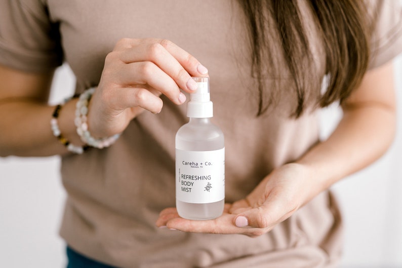 May include: A clear glass bottle with a white label that reads "Careha + Co. Refreshing Body Mist".