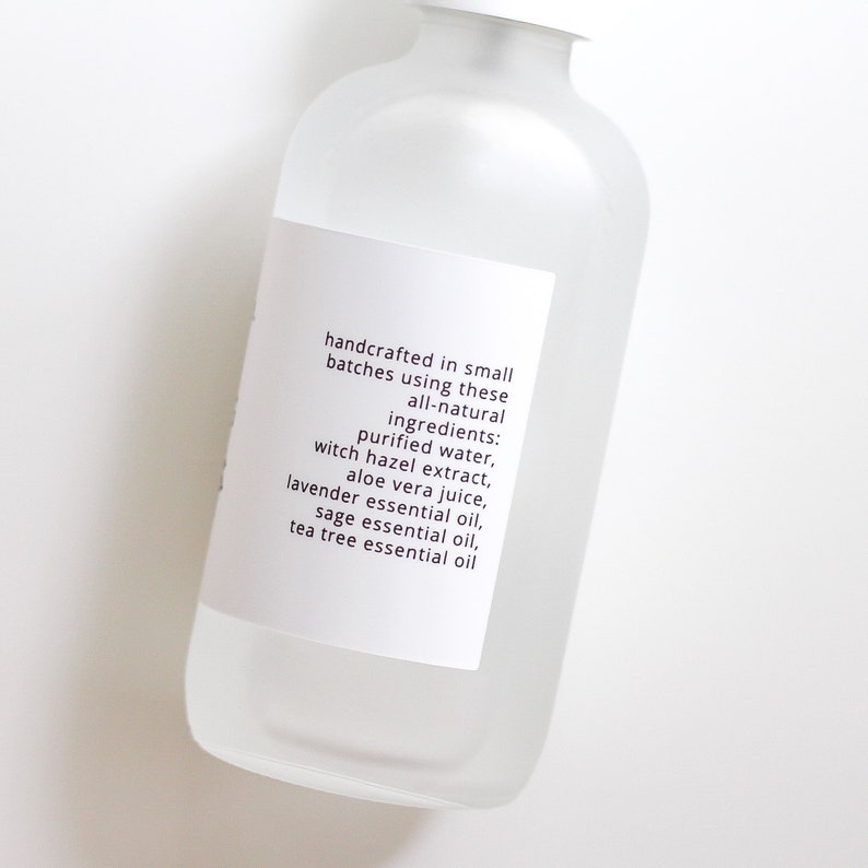 May include: A clear glass bottle with a white label that reads "handcrafted in small batches using these all-natural ingredients: purified water, witch hazel extract, aloe vera juice, lavender essential oil, sage essential oil, tea tree essential oil"