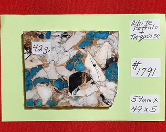 May include: A close-up of a piece of white buffalo turquoise, a type of gemstone, with a blue and white pattern. The stone is 5.9 cm x 4.9 cm and weighs 42 grams. It is labelled "White Buffalo Turquoise #1791".