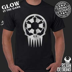 May include: Black t-shirt with a silver glow-in-the-dark design of a skull with a star wars inspired symbol inside the skull. The text "Glow in the Dark" is at the top of the shirt. The text "The Original Design Accept No Imitations" is in a circle with a star in the center.