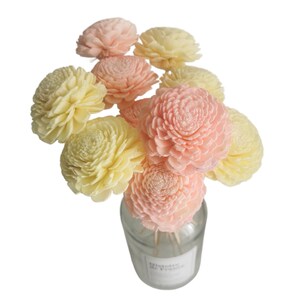 May include: A bouquet of sola wood flowers in a clear glass vase. The flowers are a mix of light pink and cream colours.