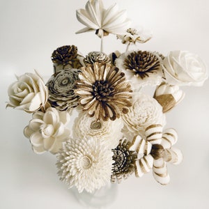 Op de afbeelding: Een boeket van witte en bruine sola-houten bloemen. De bloemen zijn gerangschikt in een vaas en omvatten een verscheidenheid aan vormen en maten.