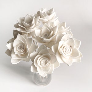May include: A bouquet of white sola wood flowers arranged in a clear glass vase. The flowers are made of sola wood and have a delicate, papery texture.