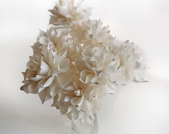 May include: A bouquet of white sola wood flowers arranged in a clear glass vase. The flowers are made from sola wood, which is a natural material that is lightweight and durable.