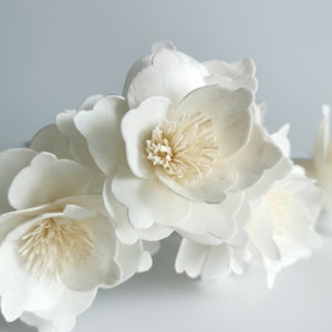 May include: A cluster of white sola wood flowers with a delicate, layered design. The flowers have a natural, slightly textured finish and a creamy white colour.
