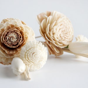May include: A set of wooden flower diffuser sticks with a brown and white flower, a white flower, and a white tulip-shaped diffuser. The sticks are made of natural wood and are designed to diffuse essential oils.