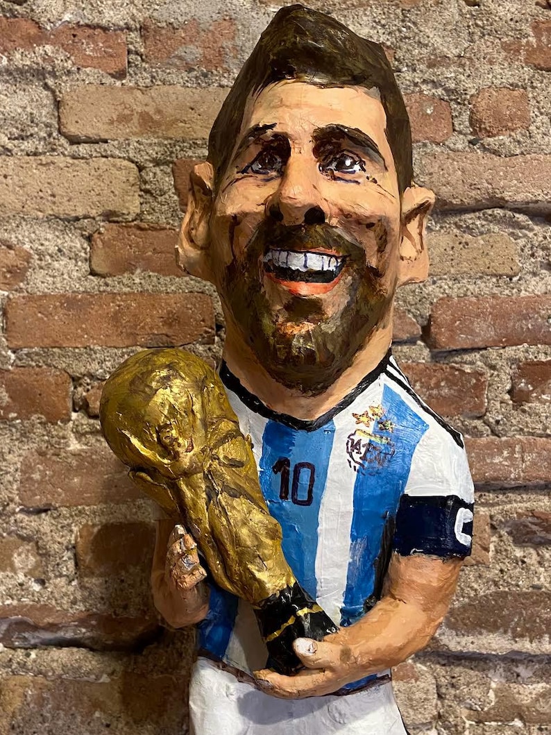 May include: A caricature of a soccer player wearing a blue and white striped jersey with the number 10 on the front. He is holding a gold trophy in his right hand and smiling.