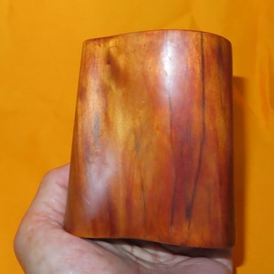 May include: A smooth, rectangular wooden block with a polished finish, displaying a warm gradient of orange, brown, and deep reddish-brown tones with visible natural wood grain patterns throughout the surface of the object.