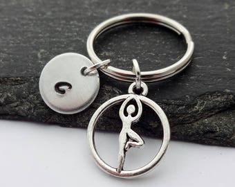 May include: Silver keychain with a yoga pose charm and a round charm with the letter G.