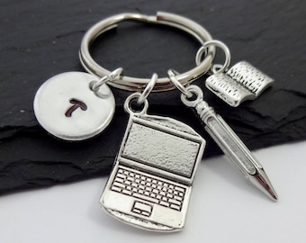 May include: Silver keyring with a laptop charm, a pencil charm, a book charm, and a round charm with the letter T.