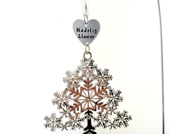 May include: A silver snowflake ornament with a heart-shaped tag that reads "Nadolig Llawen".