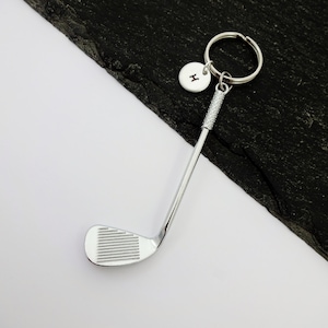 Puede incluir: Llavero de club de golf plateado con un dije inicial plateado. El dije tiene la letra "H" grabada.