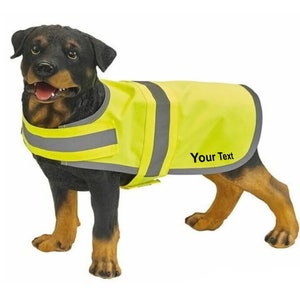 May include: A black and brown dog wearing a bright yellow safety vest with reflective strips. The vest has the text "Your Text" printed on it.