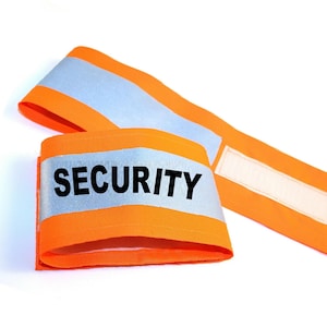 Puede incluir: Brazalete reflectante naranja y plateado con la palabra "SECURITY" impresa en negro.