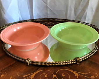 May include: Two vintage glass bowls, one pink and one green, with a fluted design. The bowls are sitting on a mirrored tray with a gold rope design.