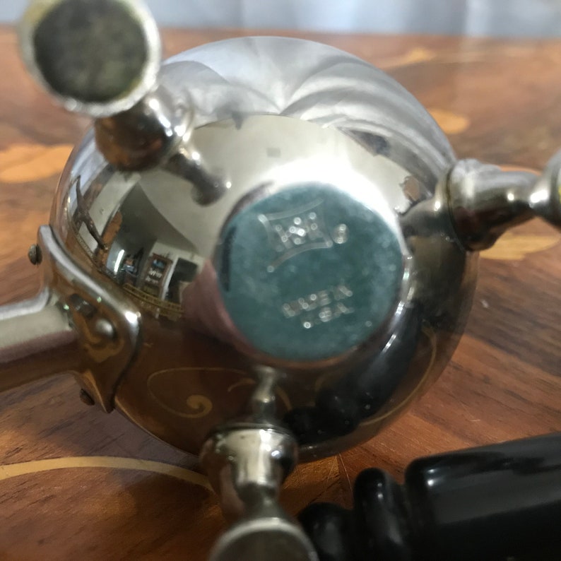 May include: Silver sugar dispenser with a round body and three spouts. The bottom of the dispenser has the text "Made in U.S.A."