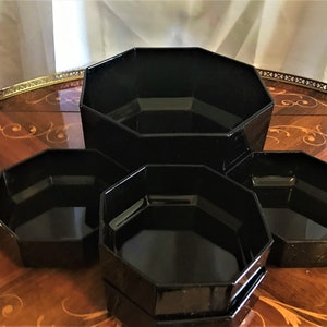 Pode incluir: Conjunto de quatro tigelas de vidro octogonais pretas de tamanhos diferentes. As tigelas est&atilde;o empilhadas em uma mesa de madeira.