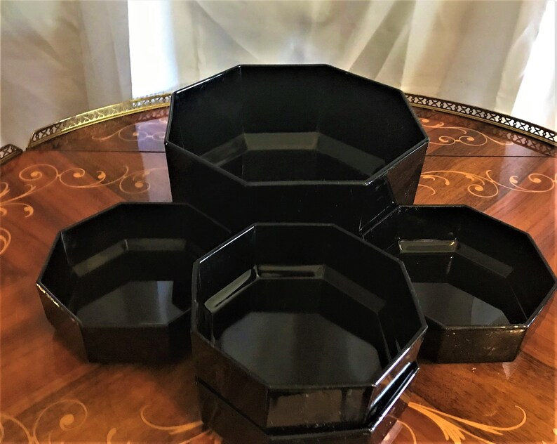 Pode incluir: Conjunto de quatro tigelas de vidro octogonais pretas de tamanhos diferentes. As tigelas est&atilde;o empilhadas em uma mesa de madeira.