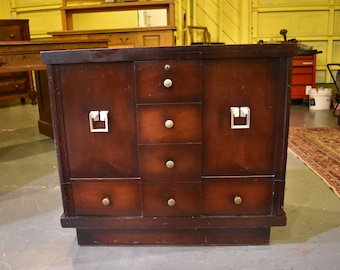 May include: A dark brown wooden cabinet with four drawers and two doors. The cabinet has silver metal handles and a raised base.