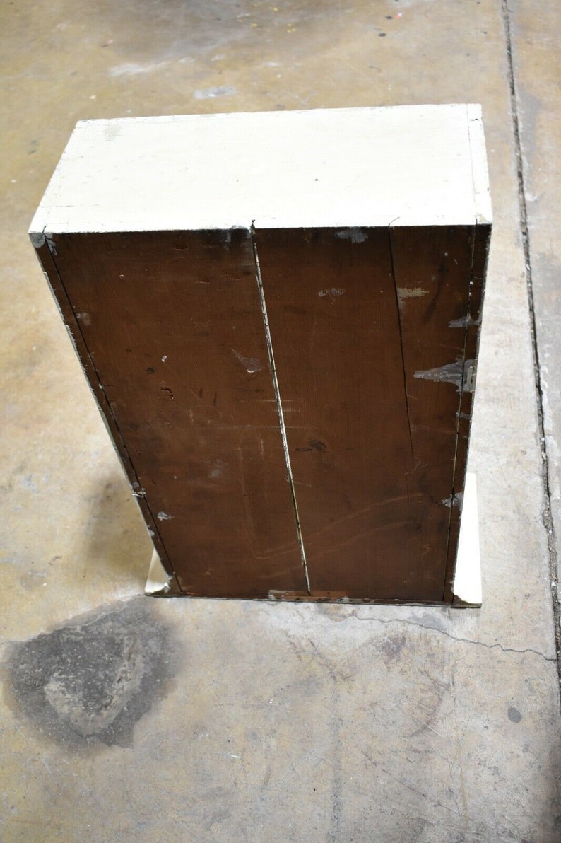 May include: A white wooden cabinet with a brown wooden back. The cabinet has a simple design and is in good condition.
