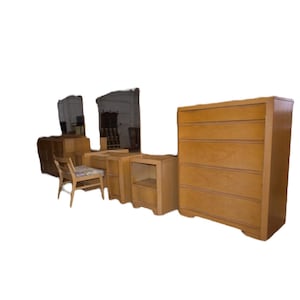 May include: A bedroom furniture set featuring a tall five-drawer chest, a vanity desk with a matching chair, and a nightstand. Each piece is crafted from light-toned wood with a smooth finish, clean lines, and integrated drawer pulls.