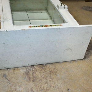 May include: White wooden display case with glass shelves and a decorative trim. The case has a simple design and is in good condition.
