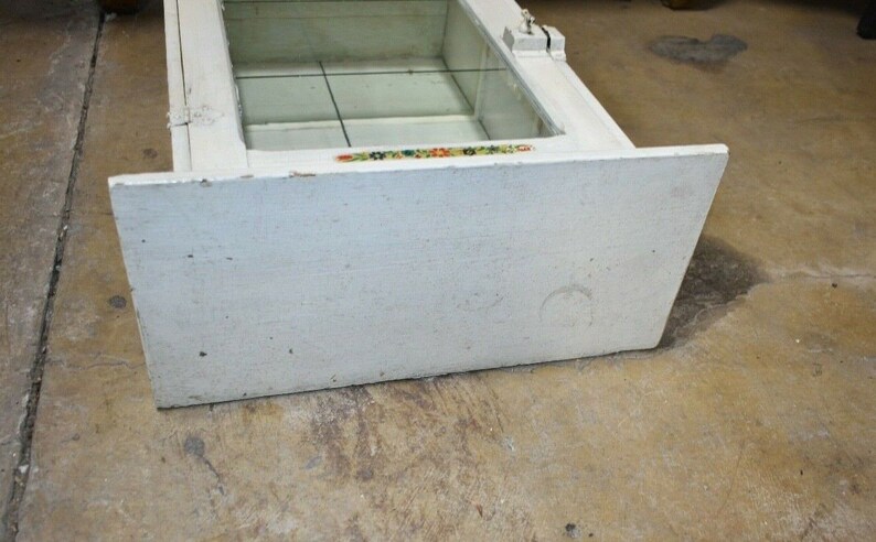 May include: White wooden display case with glass shelves and a decorative trim. The case has a simple design and is in good condition.