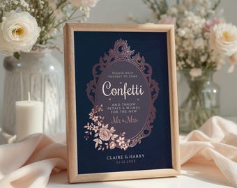 May include: A framed navy blue sign with the word "Confetti" in a decorative oval frame. The sign includes the text "Please help yourself to some" and "And throw petals & wishes for the new Mr & Mrs". The sign is decorated with floral elements.