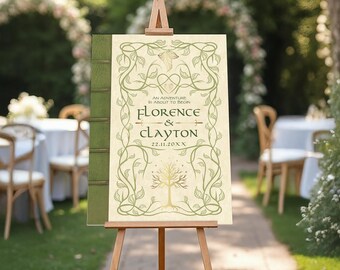 May include: A wedding welcome sign on a wooden easel. The sign is designed to look like a book, with a green spine and a cream-colored front featuring the names "Florence & Clayton" and the date. The design includes decorative vines and a tree.