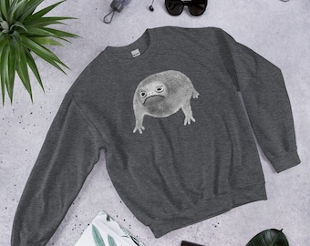 Puede incluir: Una sudadera gris oscuro con un gráfico blanco de una rana de dibujos animados con una expresión gruñona. La rana está de pie sobre sus cuatro patas y tiene un cuerpo redondo.