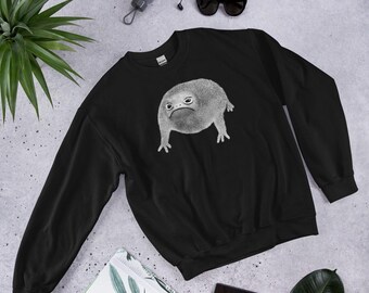 Puede incluir: Sudadera negra con un gráfico blanco de una rana con una expresión de enfado.