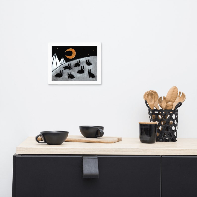May include: A black and white illustration of a crescent moon with a golden glow, two white mountains, and a group of black rabbits on a white background.