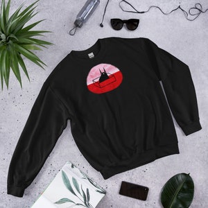 May include: Black sweatshirt with a red and pink circle graphic featuring a black cat in a box.