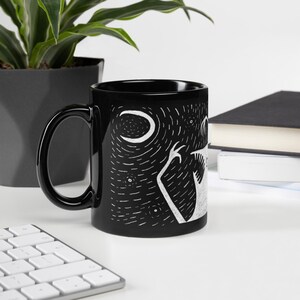 Pode incluir: Caneca de cer&acirc;mica preta com uma ilustra&ccedil;&atilde;o branca de uma criatura sob uma lua crescente e estrelas. A caneca tem uma al&ccedil;a preta e um acabamento brilhante. O design &eacute; uma representa&ccedil;&atilde;o art&iacute;stica e caprichosa de uma cena noturna.