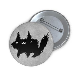 May include: A black and white button featuring a cartoon black cat with a fluffy tail and a friendly expression.