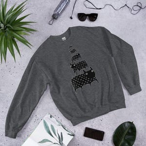 May include: A dark gray sweatshirt with a black and white graphic of a stack of cats. The cats are all facing the same direction and have a simple, stylized design.