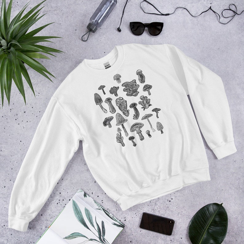 May include: White sweatshirt with a black and white illustration of various mushrooms. The sweatshirt has long sleeves and a crew neck.