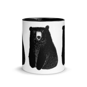 May include: White ceramic mug with a black rim and handle. The mug features a black and white illustration of three bears sitting on a white background.