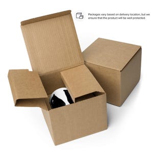 May include: A brown cardboard box with a smaller brown cardboard box inside. The smaller box is open and contains a white mug with a black and white design.
