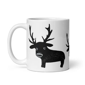 May include: White ceramic mug with a black and white illustration of a deer with large antlers. The deer has a wide-eyed, surprised expression and is looking directly at the viewer.