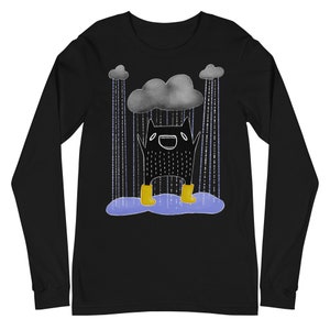 May include: Black long-sleeved t-shirt featuring a cartoon illustration of a black monster wearing yellow wellies and standing under a grey cloud with rain falling. The monster is smiling and has its arms raised.