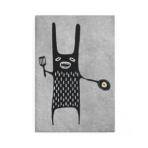 May include: A black monster with long ears and a white dotted body is holding a spatula in one hand and a frying pan with a fried egg in the other. The monster has a wide smile and is standing on a gray background.