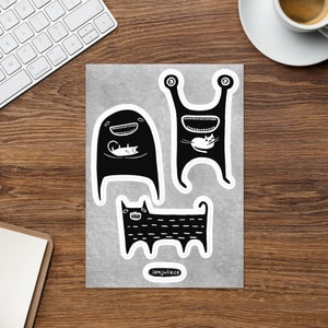 May include: Three black and white stickers featuring cartoon monsters holding cats. The stickers are on a grey background with the text "iamjulie.ca" at the bottom.