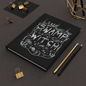 May include: Black notebook with a white illustration of a swamp witch and the words "Swamp Witch" on the cover.