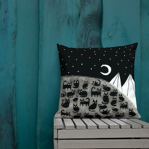 May include: A black and white pillow with a design of a night sky with a crescent moon and mountains. There are many black cats in the foreground of the design.
