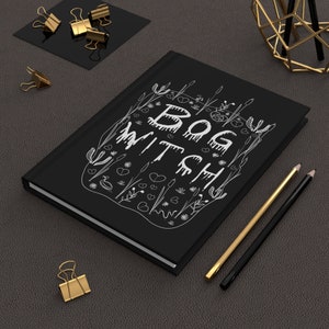 May include: Black notebook with a white design of a swamp scene and the text "BOG WITCH".