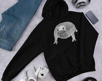 Puede incluir: Sudadera con capucha negra con un gráfico blanco de una rana con una expresión de enfado. La rana está de pie sobre sus cuatro patas y tiene un cuerpo redondo.