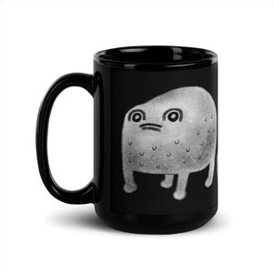 May include: Black ceramic coffee mug with a white cartoon illustration of a gray, blob-like creature with large eyes and a frown.