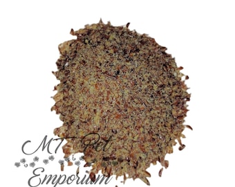 May include: A mound of ground flax seeds with a coarse, textured appearance in shades of dark brown and golden yellow. The text MT Pet Emporium is printed in a dark gray script font at the bottom left of the image against a white background.