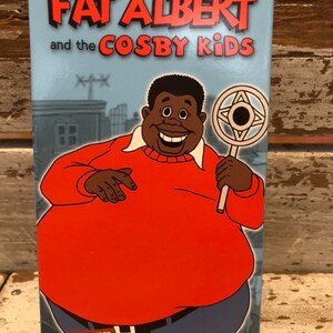 May include: A VHS tape box featuring the cartoon character Fat Albert from "Fat Albert and the Cosby Kids." The box has a blue background with the show's title in red and the character in a red sweater. The bottom of the box reads "CREATIVITY • MOVING."